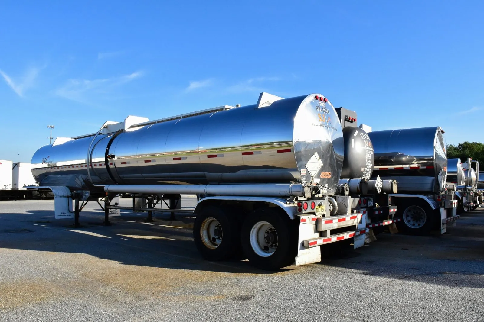Polished stainless steel fuel tanker trailer under a blue sky